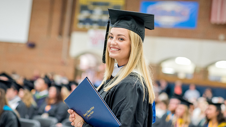 Student with diploma at commencement.