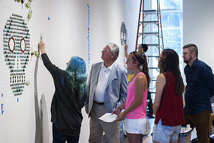 Installation artist Jennifer Angus works with students, and even President Jake Schrum, to install thousands of insects on the gallery wa...