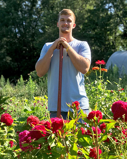 Student takes a break from Service Plunge to pose in the garden.