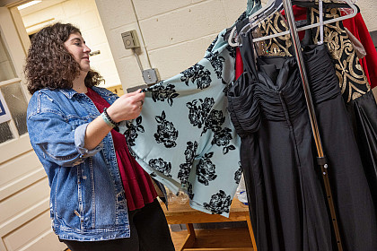 A student picks out a dress from the clothes rack.