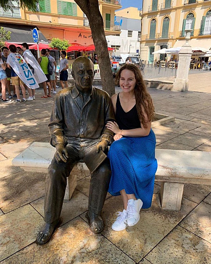 E&H student sitting next to the Statue of Picasso in Spain.