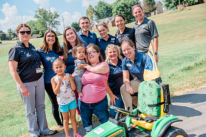 Students and faculty gather with Zavier and his mother with the modified tractor.