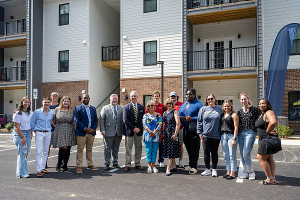    Student resident advisors, current residents and administrators pose in front of the new University Apartments at Emory & Henry 