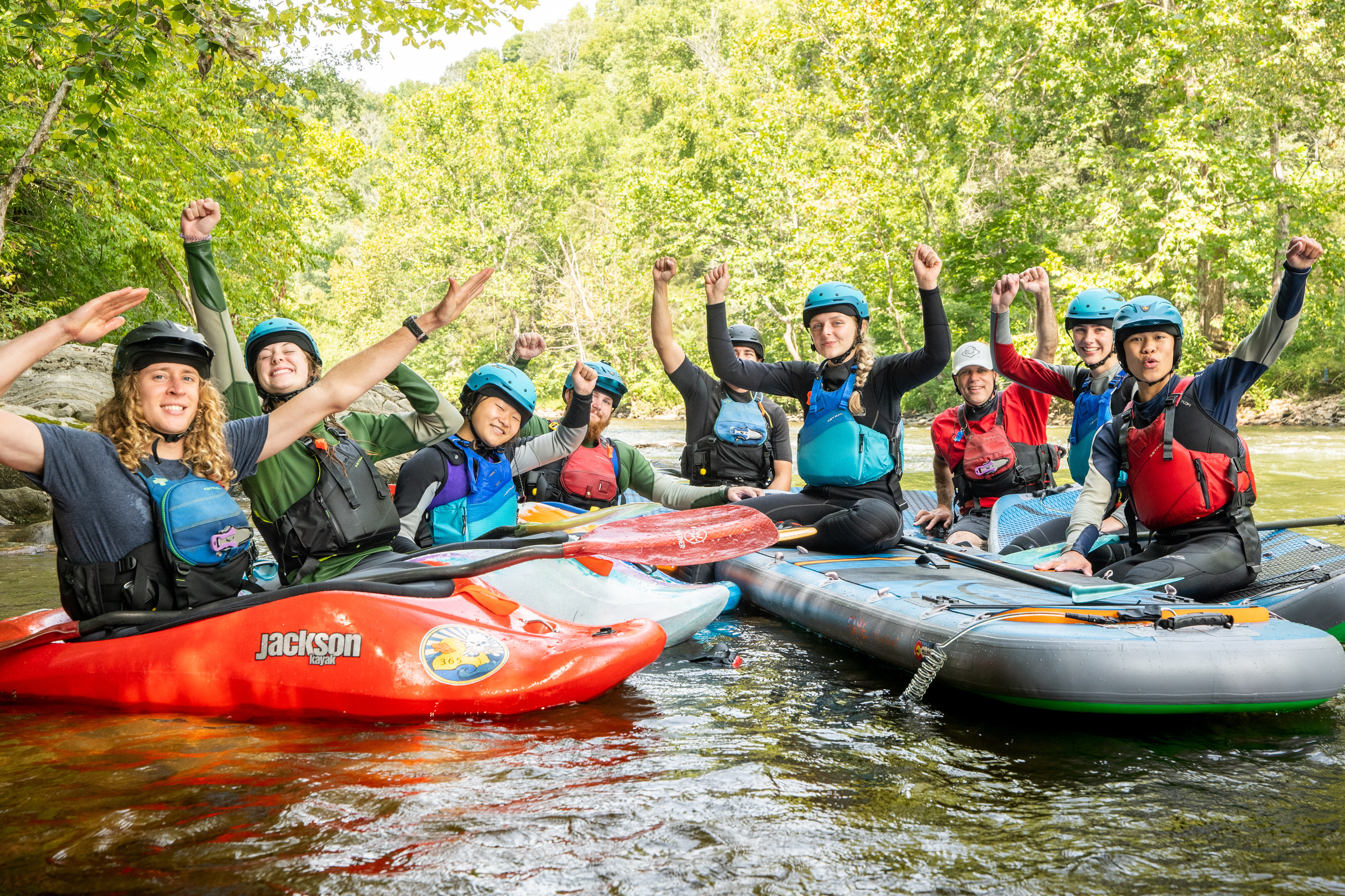 A group of kayaking students posing on the river